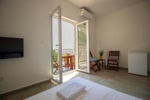 ein Zimmer mit Bett und Balkon mit Fernseher in der Unterkunft Apartments ZINA in Lokva Rogoznica