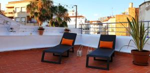 2 Stühle mit orangefarbenen Kissen auf dem Balkon in der Unterkunft Les Llambrich - Apartamentos turísticos in L'Ampolla