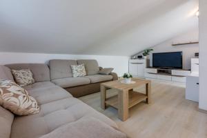 ein Wohnzimmer mit einem Sofa und einem TV in der Unterkunft KONI in Crikvenica