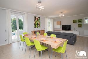 a dining room with a table and green chairs at Villa Bocciolo, piscina, giardino, vasca idromassaggio in Manerba del Garda