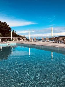 a swimming pool with chairs and the ocean in the background at Le Cardinal - Belle-Ile-en-Mer in Sauzon