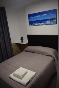 Una cama con dos toallas blancas encima. en PENSION TASAGA, en O Pino 
