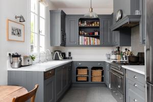 a kitchen with gray cabinets and white counter tops at Les Jardins du Panthéon in Paris
