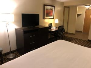a hotel room with a bed and a desk with a television at Ramada by Wyndham Lindsay in Lindsay