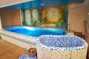 a bathroom with a tub covered in blue and white tiles at Armenia Hotel in Tula