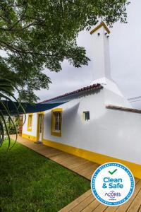 une maison blanche et jaune avec un panneau devant elle dans l'établissement Casa Villa Cottage, à Ponta Delgada