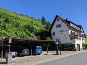 a white building with cars parked in front of it at Hotel Pension Winzerhaus in Bacharach