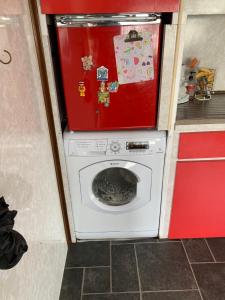 a washing machine in a kitchen with a red refrigerator at Vintage, Circus Holiday Home in Mablethorpe