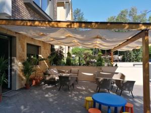 a patio with tables and chairs under awning at APARTMANI SUNNY SIDE in Vrnjačka Banja