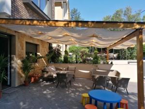 a patio with tables and chairs under awning at Apartmani Sunny side sa otvorenim bazenom-besplatan parking in Vrnjačka Banja