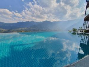 una grande piscina d'acqua con montagne sullo sfondo di Sapa Clay House - Mountain Retreat a Sa Pa