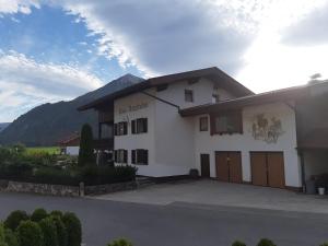 um grande edifício branco com uma montanha ao fundo em Haus Bergfrieden em Achenkirch