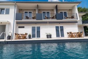 una casa con sillas y una piscina en CURICTA Design Apartments en Krk