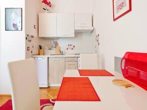 eine Küche mit weißen Schränken und einem roten Gerät in der Unterkunft Apartments Brioni Colors in Pula