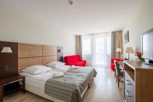 a hotel room with a bed and a desk and red chairs at Apartamenty Spa Promenada in Kołobrzeg