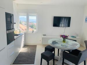 uma cozinha branca com uma mesa e cadeiras e uma televisão em Trogir Penthouse IVY em Trogir