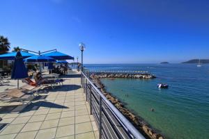 a beach with chairs and umbrellas and people in the water at Hotel San Terenzo in Lerici