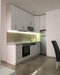 a kitchen with white cabinets and a sink and refrigerator at Apartman SIMS in Bijeljina