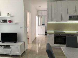 a kitchen with white cabinets and a table with a television at Apartman SIMS in Bijeljina
