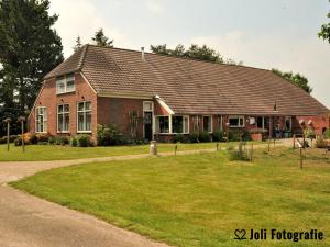 a large red brick house with a grass yard at Buitengoed Het Achterdiep in Ter Apel