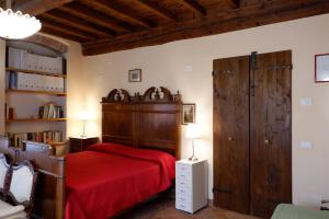 a bedroom with a red bed and a wooden door at Alla Locanda Del Cinquecento in Castrocaro Terme