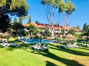 a resort with a swimming pool with chairs and trees at PUERTO BANUS Apartamento COCÓ in Marbella
