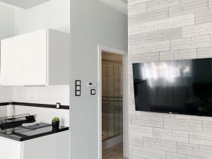 a white kitchen with a large flat screen tv on a wall at Apartament Chyba Śnisz Łańcut in Łańcut