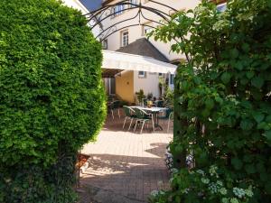einen Garten mit einem Tisch und Stühlen hinter einer Hecke in der Unterkunft Hôtel - Restaurant " Victor Hugo" in Vianden