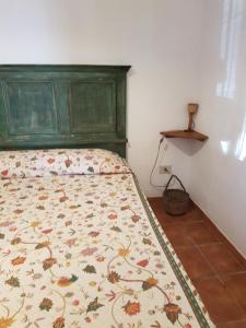 a bed with a green head board in a bedroom at dammuso rosa in Pantelleria