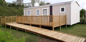 une grande terrasse en bois avec une petite maison dans l'établissement Camping le Frêche à l'Âne, à Pléboulle