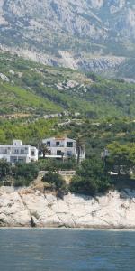 a house on top of a hill next to the water at Apartments Tri Palme in Baška Voda