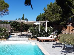 a swimming pool with chairs and an umbrella and an umbrella at Le mazet de l'Amathye in Aramon