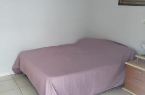 a bedroom with a bed with a purple blanket and a dresser at Apartamento confortável em Meia Praia - 200 metros da praia in Itapema