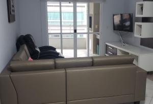 a living room with a brown couch and a television at Apartamento confortável em Meia Praia - 200 metros da praia in Itapema