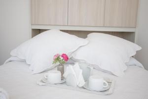 - un plateau avec des tasses, des soucoupes et des fleurs sur le lit dans l'établissement Lovely apartment near the sea 25 bis Promenade des Anglais, à Nice