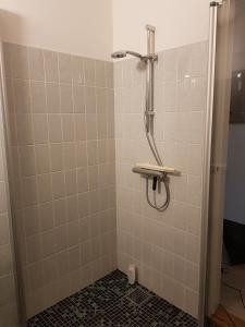 La salle de bains est pourvue d'une douche et de carrelage blanc. dans l'établissement Shalom, à Gjerlev