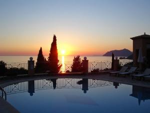 a swimming pool with a sunset in the background at Dina's Paradise in Agios Gordios