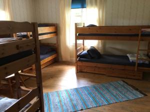 a room with three bunk beds and a rug at Vandrarhem Svänö in Hillerstorp