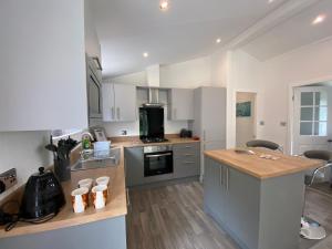 a kitchen with white cabinets and a wooden counter top at Fox Lodge at Owlet Hideaway - with Hot Tub, Near York in York