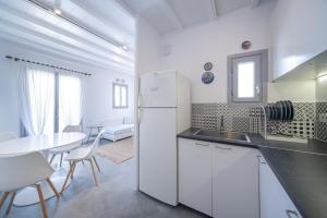 a kitchen with a white refrigerator and a table at Myconian Relax House with swimming pool in Ano Mera