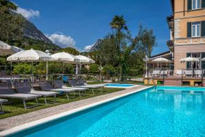 einen Pool in einem Hotel mit Stühlen und Sonnenschirmen in der Unterkunft Hotel Maderno in Toscolano-Maderno