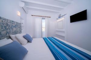 a white bedroom with a bed with blue pillows at Myconian Relax House with swimming pool in Ano Mera