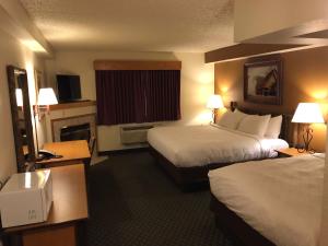 a hotel room with two beds and a fireplace at AmericInn by Wyndham Cody in Cody