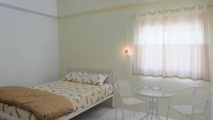 合艾Baankanjana的一间卧室，里面有一张床、一张桌子和几把椅子。