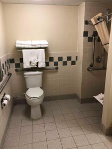 a bathroom with a toilet and towels on a wall at AmericInn by Wyndham Cody in Cody