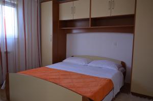 sypialnia z łóżkiem z pomarańczowym kocem w obiekcie Apartments Tomas w mieście Betina
