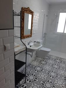 La salle de bains blanche est pourvue d'un lavabo et d'un miroir. dans l'établissement Casa de Antoniana, à Gilena