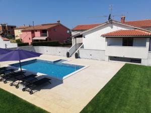 a swimming pool with chairs and an umbrella in a yard at Holiday Home Victoria in Poreč