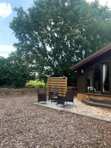 a patio with two chairs and a house at Squirrel Lodge at Owlet Hideaway - with Hot Tub, Near York in York