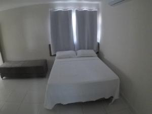 a small bedroom with a white bed and a window at Pousada Tambaú in João Pessoa